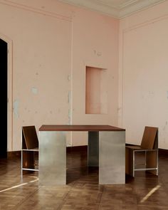 an empty room with two chairs and a table in the middle, one chair is missing