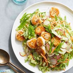 a white plate topped with salad and scallops