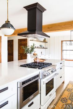 a kitchen with two ovens and an island in the middle of it, next to a potted plant