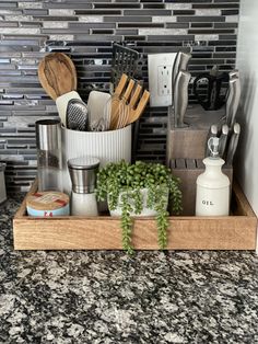 kitchen utensils and cooking utensils in a wooden tray on a granite countertop