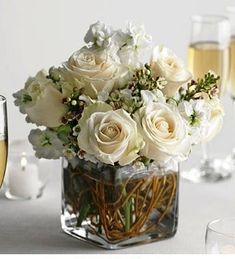 a vase filled with white flowers next to wine glasses