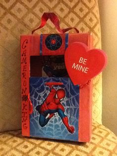 a red heart shaped box sitting on top of a chair next to a spiderman book