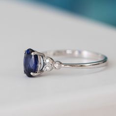 a blue sapphire and diamond ring sitting on top of a table