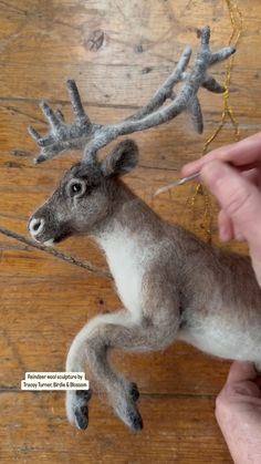 a needle - felt deer ornament being held by someone's hand