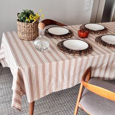 the table is set for four with plates and flowers in a basket on top of it