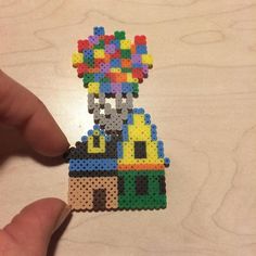 a hand holding a small piece of bead art with a building on the top