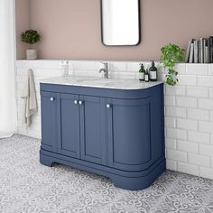 a bathroom with a blue vanity and white tile flooring, along with a mirror on the wall