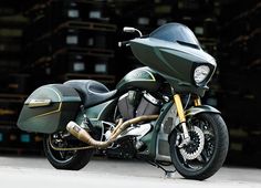 a green motorcycle parked in front of stacks of boxes