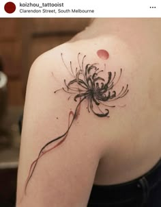 the back of a woman's shoulder with a flower tattoo on it