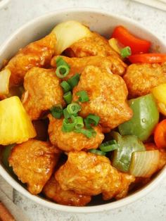 a bowl filled with meat and vegetables on top of a white countertop next to chopsticks