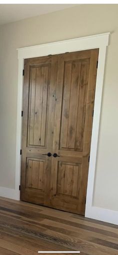 an empty room with two wooden doors and hard wood flooring on one side, the door is open