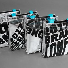 three bags with blue handles are lined up against each other on a gray surface, one is empty and the other has black and white designs