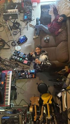 a woman sitting on top of a couch surrounded by musical instruments and other electronic equipment