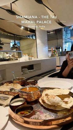 a woman taking a photo of food on a table in a restaurant with the caption, shamanna the taj mama palace