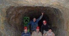 four men wearing red helmets are standing in a cave with their arms up and one man is holding his hand up