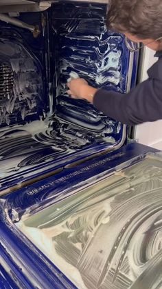 a man is painting the inside of an oven with blue paint and silver flakes