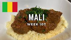 a white plate topped with rice and meat next to a flag on the wall behind it