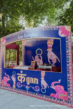 a blue and pink food cart sitting on the side of a road next to trees