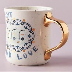 a white coffee cup with gold handles and the words that love are printed on it