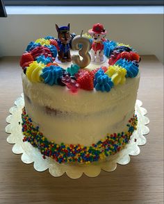 a birthday cake that has the number three on it and is decorated with colorful sprinkles