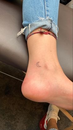 a woman's foot with a small crescent tattoo on it