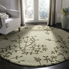 a living room area with a white chair and large round rug on the hardwood floor