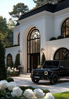 a black mercedes g class parked in front of a large white house with roses around it