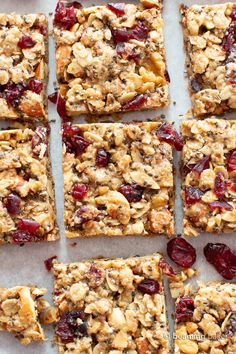 homemade granola bars with dried cranberries and nuts are cut into squares on a piece of parchment paper