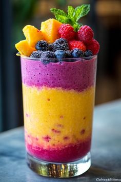 a glass filled with fruit and berries on top of a table