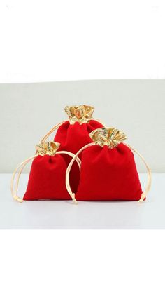 three red velvet bags with gold handles and bows on the top, one is empty