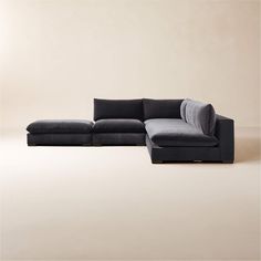 a black sectional couch sitting on top of a white floor next to a beige wall