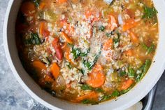 a bowl of soup with carrots, spinach and parmesan cheese in it