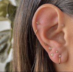 a close up of a person wearing ear piercings with gold colored beads and stars on them