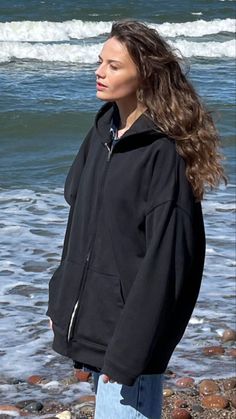 a woman standing on top of a beach next to the ocean