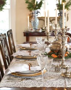 a dining room table is set with place settings and silver candlesticks on it