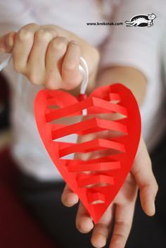 a person holding a heart shaped object in their hands with the string attached to it