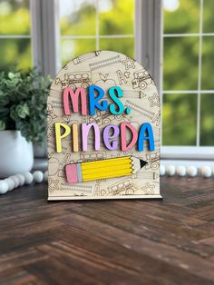 a wooden sign that says mrs pineda with pencils and crayons on it