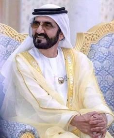 a man sitting in a chair wearing a white and yellow outfit with gold trimmings