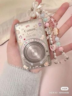 a person is holding a camera in their hand with pearls and beads on it's wrist