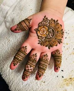 someones hand with henna tattoos on it, showing the intricate designs and colors