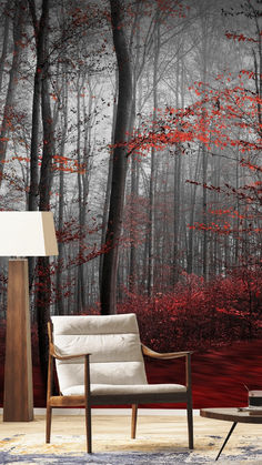 a chair and lamp in front of a wall mural with red leaves on the trees