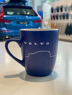 a blue coffee cup sitting on top of a white table next to a blue car