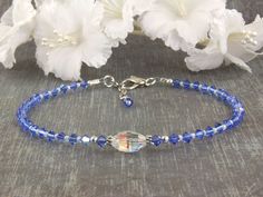 "The sparkling handmade 'Atlantis' is your 'Something Blue' sapphire wedding beaded anklet. Brides have been wearing something blue for centuries as it is tied to Old English \"Something old, something new, something borrowed, something blue.\" This is the perfect gift for her wedding day. This beaded anklet was designed with blue Swarovski crystal, tiny cream Charlotte glistening seed beads, Bali 925 silver and finished with a marine dolphin lobster clasp. Available in light sapphire, sapphire Adjustable Blue Crystal Bracelet For Anniversary, Adjustable Blue Beaded Bracelets For Wedding, Adjustable Blue Bracelets For Anniversary, Adjustable Blue Crystal Bracelet For Wedding, Adjustable Crystal Anklets For Wedding, Adjustable Sapphire Bracelets For Wedding, Elegant Blue Anklets For Gifts, Elegant Blue Anklets For Gift, Blue Round Beads Bracelet For Wedding