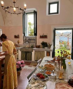 a woman in a yellow dress standing at a table with plates and food on it