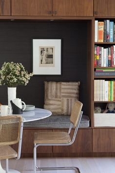 a dining room table with chairs and bookshelf in the back wall behind it