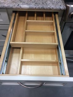 an open drawer in a kitchen with granite counter tops