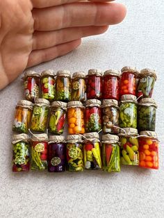 there are many jars filled with different types of vegetables in each jar and the person is holding out their hand