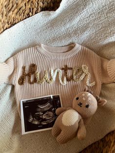 a knitted sweater with the word hope written in cursive letters next to a teddy bear