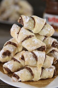 a pile of chocolate filled pastries on a white plate with powdered sugar in the background