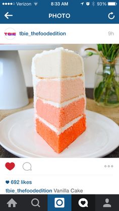 a slice of cake sitting on top of a white plate next to a vase with flowers